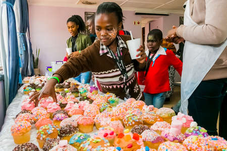 Johannesburg, South Africa - March 24, 2018: African children receiving cupcakes at Soup Kitchen volunteer community outreach program at orphanageのeditorial素材