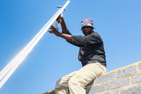Soweto, South Africa - September 05, 2009: Community Outreach program helping to install metal roofing on a small affordable house in local townshipのeditorial素材