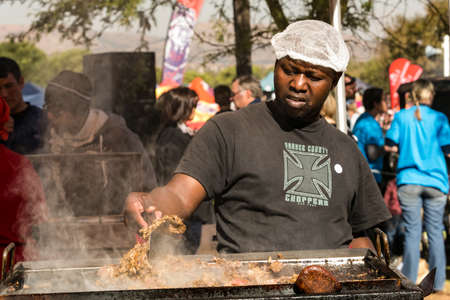 Johannesburg, South Africa - June 7, 2014: Male vendor working a BBQ Grill of steak, chops and sausages at stall at farmer's marketのeditorial素材