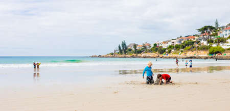 Cape Town, South Africa - March 13 2019: Kids playing on Fish Hoek beach on a cloudy dayのeditorial素材