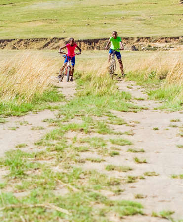 Harrismith, South Africa - October 18 2012: African Children riding a bike in rural a villageのeditorial素材