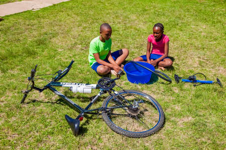 Harrismith, South Africa - October 18 2012: African Children fixing a puncture on a bikeのeditorial素材