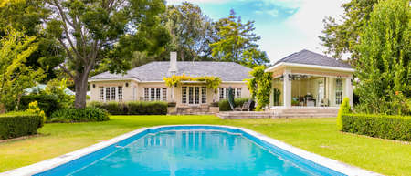 Wide angle view of Exterior of Upmarket wealthy suburban mansion house with landscaped garden and...