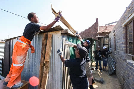 Soweto, South Africa - September 05, 2009: Community Outreach program helping to install metal roofing on a small affordable house in local townshipのeditorial素材