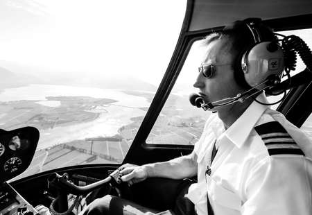 Hermanus, South Africa - July 20, 2009: Caucasian male helicopter pilot flying a R44 type chopper over rural areaのeditorial素材