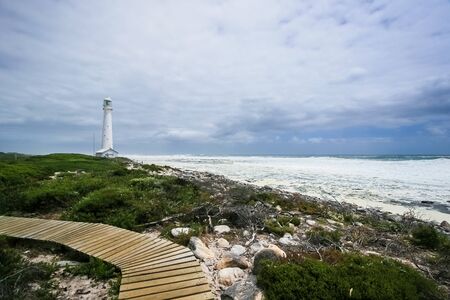Lighthouse on a rugged coastline during the daytime. Photographed in Cape Town South Africa on the West coast side of the peninsulaの写真素材
