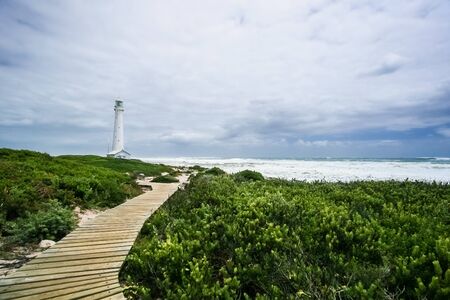 Lighthouse on a rugged coastline during the daytime. Photographed in Cape Town South Africa on the West coast side of the peninsulaの写真素材