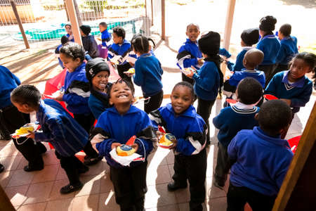 Johannesburg, South Africa - June 13, 2014: Young African Preschool kids eating in the playground of a elementary schoolのeditorial素材