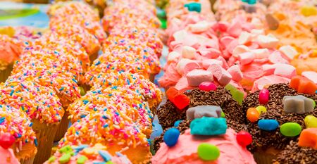 Brightly colored frosted and sprinkled cupcakes at a kids party の写真素材