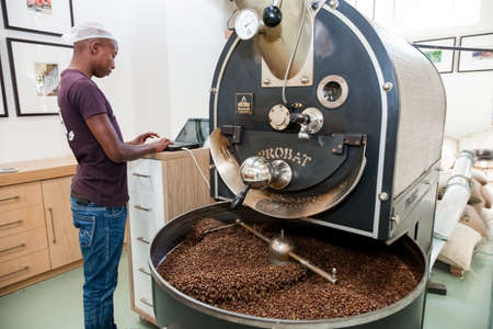 Johannesburg, South Africa - January 14, 2013: African Man operating a machine used to roast coffee beansのeditorial素材