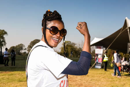 Johannesburg, South Africa - June 13, 2015: African woman flexing arm muscles in show of feminist...