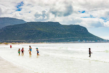 Cape Town, South Africa - March 13 2019: Swimmers frolicking in the shallow waves of Fish Hoek beachのeditorial素材