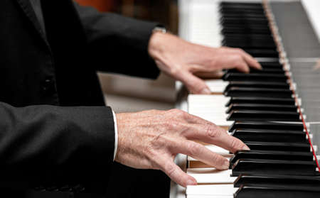 Close up side view of a Caucasian male playing a grand piano