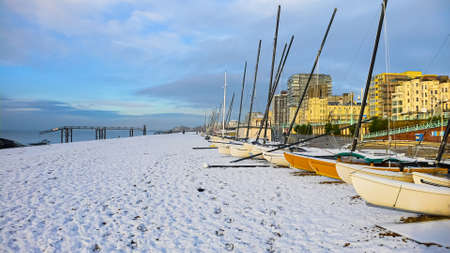 Small sail boats on a pebble beach on a frozen snowy frosty morningの写真素材