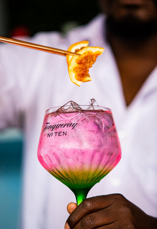 Cape Town, South Africa - December 14, 2020: Illustrative Editorial of a African barman making a pink carbonated soda based drink in a Tanqueray Gin branded cocktail glassのeditorial素材