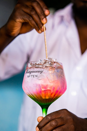 Cape Town, South Africa - December 14, 2020: Illustrative Editorial of a African barman making a pink carbonated soda based drink in a Tanqueray Gin branded cocktail glassのeditorial素材