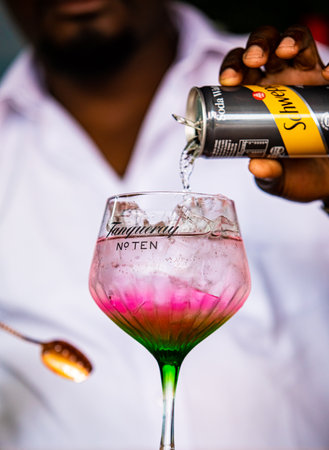 Cape Town, South Africa - December 14, 2020: Illustrative Editorial of a African barman making a pink carbonated soda based drink in a Tanqueray Gin branded cocktail glassのeditorial素材