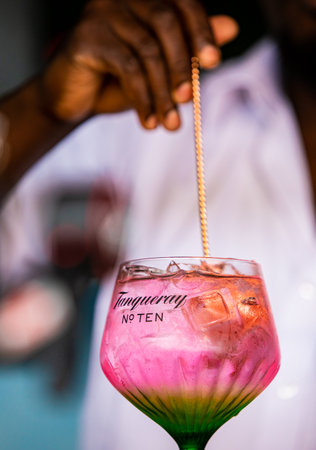 Cape Town, South Africa - December 14, 2020: Illustrative Editorial of a African barman making a pink carbonated soda based drink in a Tanqueray Gin branded cocktail glassのeditorial素材