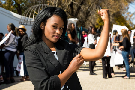 Johannesburg, South Africa - April 30, 2015: Young African girl flexing arm muscles in show of feminist powerのeditorial素材
