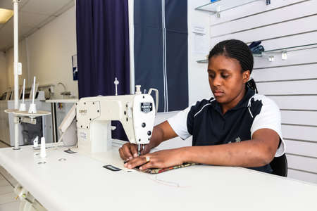 Johannesburg, South Africa - October 2, 2012: Young African woman tailer repairing clothing on a sewing machineのeditorial素材