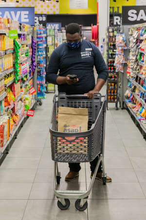 Cape Town, South Africa - September 9, 2021: Staff member picking products from shelf for express home delivery serviceのeditorial素材