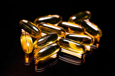 Macro Close up of Omega 3 gel capsule on a reflective black background