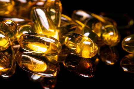 Macro Close up of Omega 3 gel capsule on a reflective black backgroundの写真素材