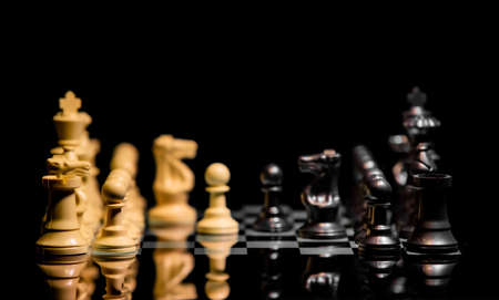 Close up of Chess pieces on a reflective mirror board surface with a plain black backgroundの写真素材