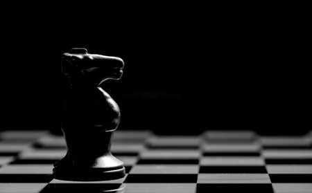 Close up of Chess pieces on a reflective mirror board surface with a plain black backgroundの写真素材