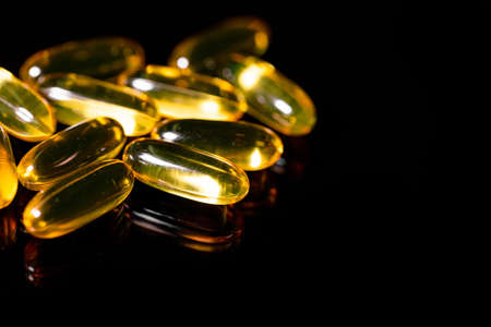 Macro Close up of Omega 3 gel capsule on a reflective black backgroundの写真素材