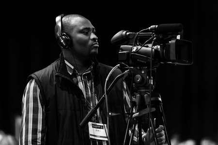 Johannesburg, South Africa - October 22, 2014: African cameraman  operating digital video camera at a conferenceのeditorial素材