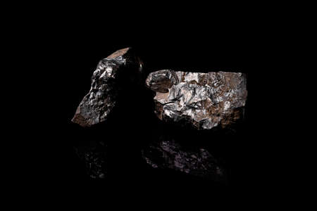 Macro Close up image of raw material Manganese Ore rock isolated on black reflective background