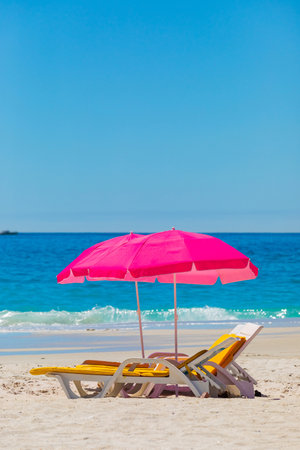 Plastic lounger chairs and parasol umbrellas on sandy beach in Camps Bay, Cape Townの写真素材