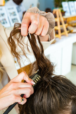 Cape Town, South Africa - November 15, 2022: Professional stylist working on young female model in hair salonの写真素材
