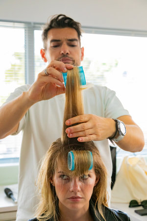Cape Town, South Africa - November 15, 2022: Professional stylist working on young female model in hair salonのeditorial素材