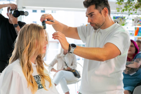 Cape Town, South Africa - November 15, 2022: Professional stylist demonstrating on young female model in hair salonのeditorial素材