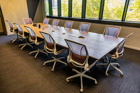 Empty executive boardroom with wooden table and fancy chairs on wheels