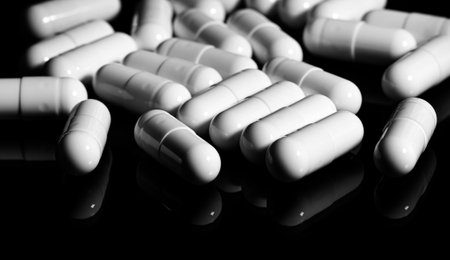 Macro Close up of white painkiller capsule on a reflective black background