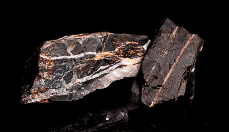 Macro Close up image of raw material Manganese Ore rock isolated on black reflective background