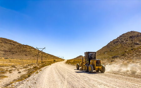 Richtersveld, South Africa - March 11, 2024: Large Caterpillar gravel dirt road grader smoothing out a road surfaceのeditorial素材