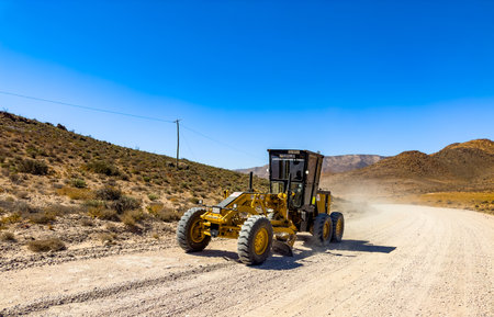 Richtersveld, South Africa - March 11, 2024: Large Caterpillar gravel dirt road grader smoothing out a road surfaceのeditorial素材
