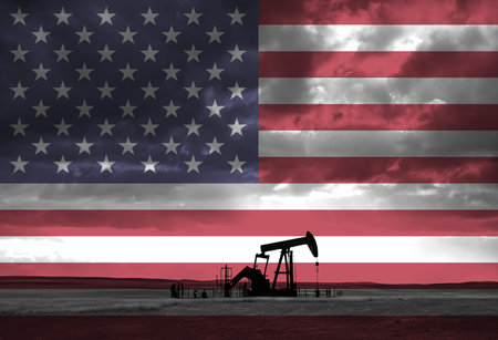 Drilling for oil in the countryside at sunset with American national flag overlayの写真素材