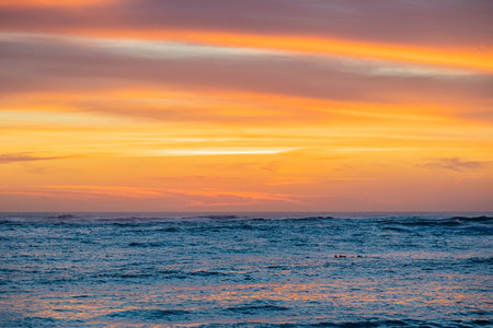Dramatic Golden sunset over tranquil beach, waves lashing the pebble coastline.