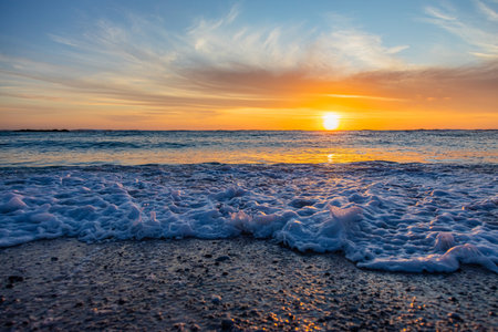 Dramatic Golden sunset over tranquil beach, waves lashing the pebble coastline, South Africa