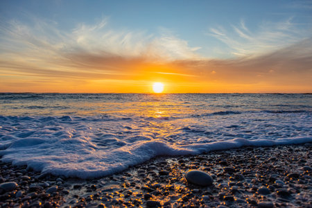 Dramatic Golden sunset over tranquil beach, waves lashing the pebble coastline, South Africa