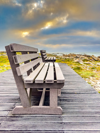 Wooden bench on decking provides idyllic coastal view, tranquil ocean horizon. South Africaの写真素材