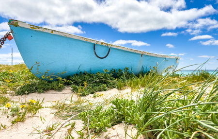 Small rowboat dinghy on a beach beneath beautiful blue azure sky, South Africaの写真素材