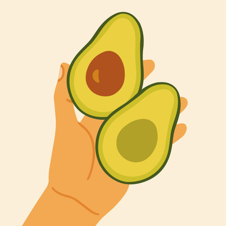 Hand holding two avocado halves.