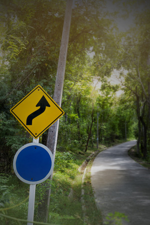 The curve traffic sign down hill and speed limit sign is blue for speed number.の写真素材