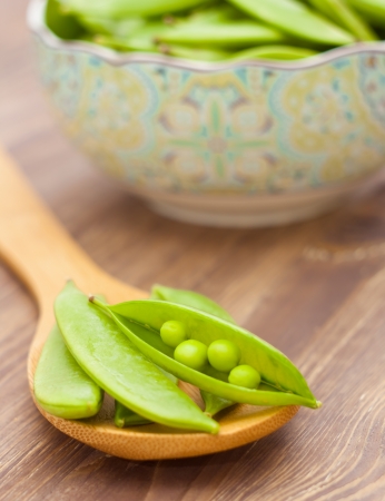Pea pods on spoon, wooden backgroundの写真素材